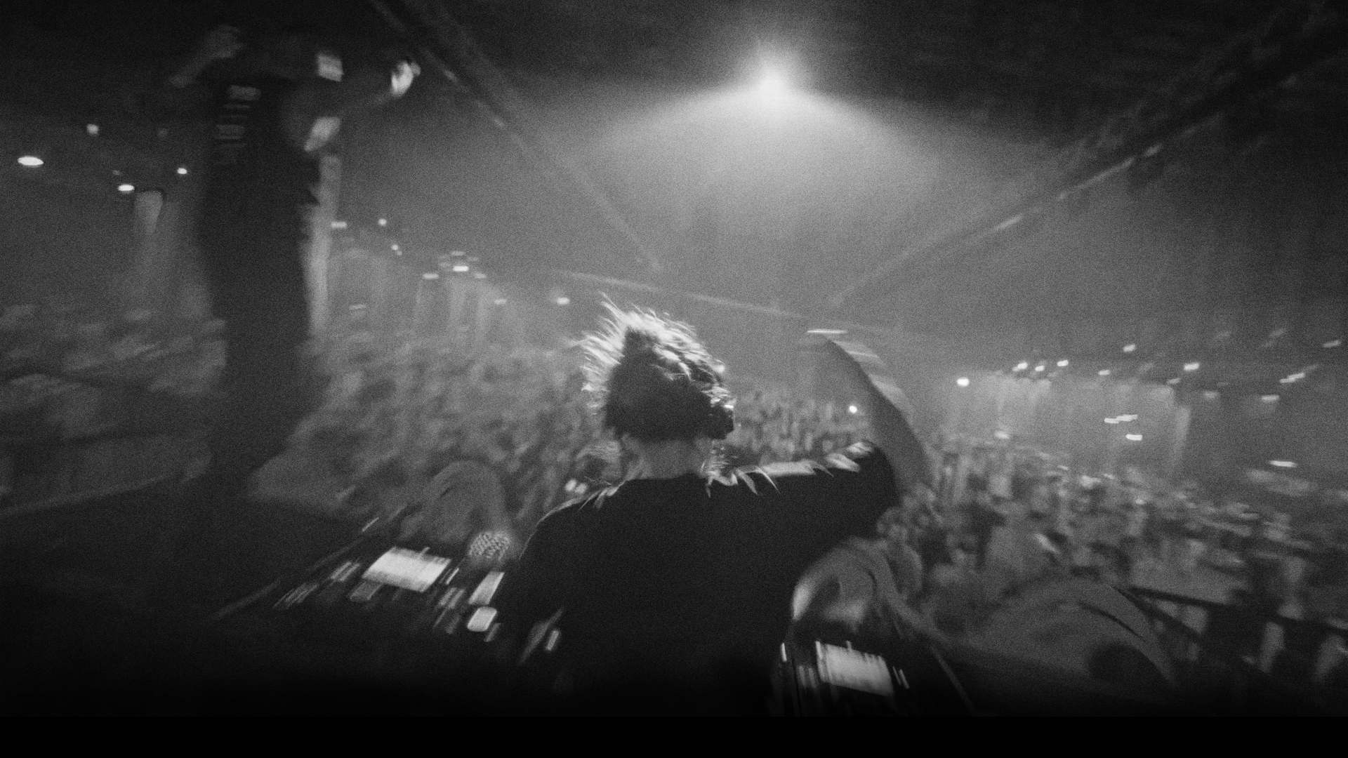 Synthsoldier performing to a full crowd under a single spotlight